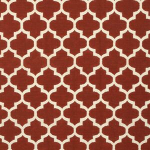 Flatwoven rug featuring a repeating cream quatrefoil trellis pattern on a deep reddish-brown field.