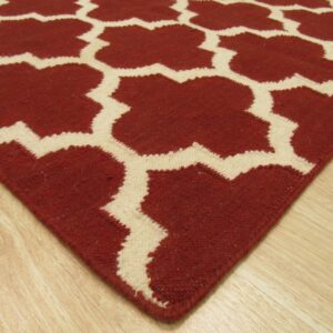 Terracotta and cream geometric rug featuring a trellis pattern resting on light wood flooring.