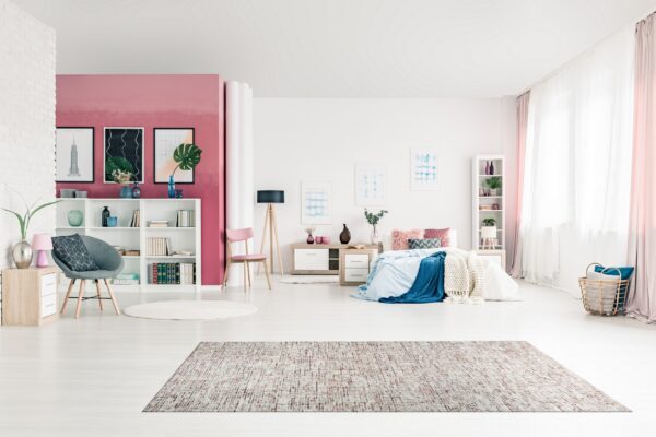 Distressed rectangular area rug in shades of pink, white, and brown on pale wood flooring.