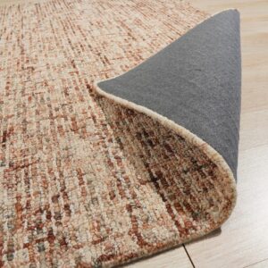A rolled rug with textured beige and rust vertical stripes reveals a gray backing on light wood flooring.