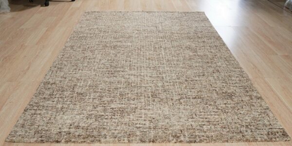 A textured beige and brown area rug with a subtle grid design sits on light wood planks.