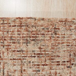 Textured loop-pile rug featuring a variegated pattern of rust, beige, and gray on light wood plank flooring.
