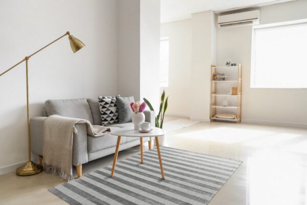 Gray and light striped rug under a coffee table, complementing a gray sofa in a bright room.