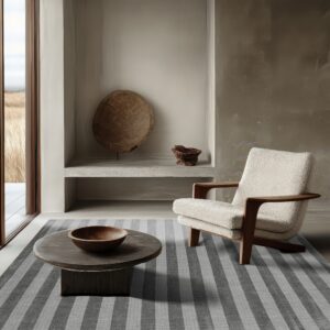 Charcoal and light grey striped rug anchors a minimalist room with a wood-framed armchair.