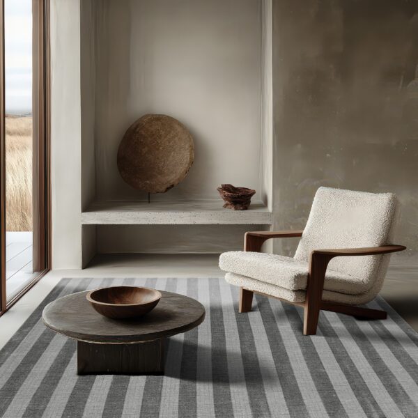 Charcoal and light grey striped rug anchors a minimalist room with a wood-framed armchair.