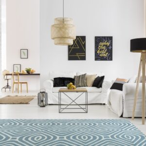 Geometric blue and white area rug on light wood flooring in a bright, modern, white living room.
