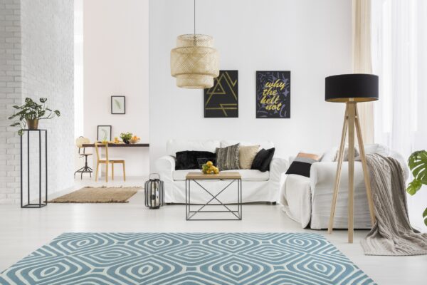 Geometric blue and white area rug on light wood flooring in a bright, modern, white living room.