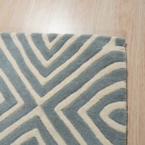 Blue and ivory high-pile rug with a carved geometric pattern rests on light wood planks.
