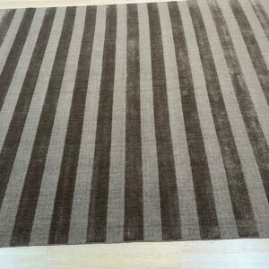 Rectangular rug featuring wide vertical stripes in dark brown and light gray on pale plank flooring.