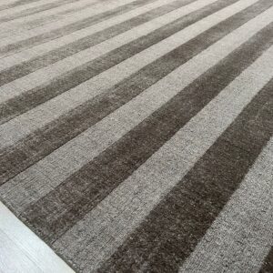 Textured striped rug featuring alternating bands of dark brown smooth pile and lighter gray loop pile on pale wood flooring.