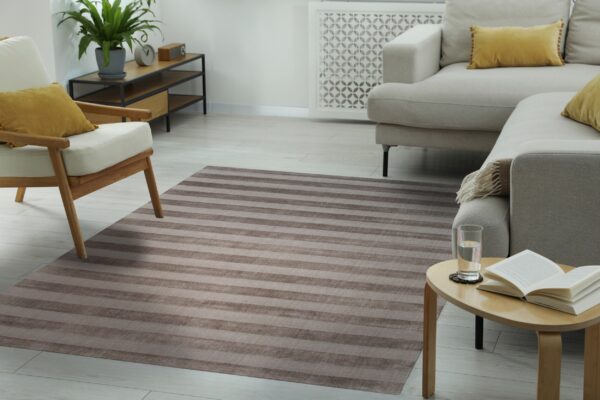 A low-pile taupe and brown striped rug anchors a modern living room with light neutral furniture.