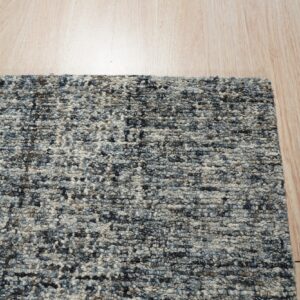 A highly textured blue and gray mottled rug with chunky loops lies on light wooden flooring.