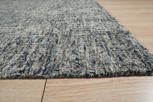 Chunky textured rug in blended blue and off-white colors on light hardwood planks.