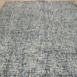Gray speckled rug with low pile texture displayed on blonde hardwood planks.