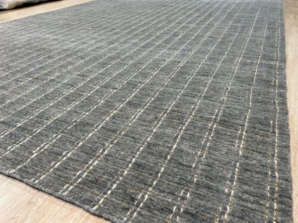 Gray textured rug with thin vertical white and beige stripes rests on light wooden flooring.