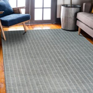 Low-pile blue-gray rug with thin vertical stripes rests on wood floors near a blue chair and plant.