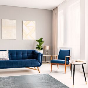 Gray textured rug on light wood flooring in a modern room with a navy blue sofa and armchair.