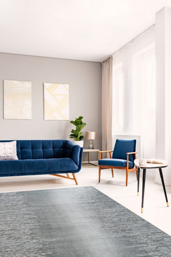 Gray textured rug on light wood flooring in a modern room with a navy blue sofa and armchair.