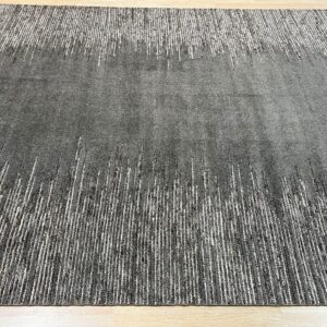 Charcoal gray textured rug featuring abstract vertical white dash patterns on a light wood floor.