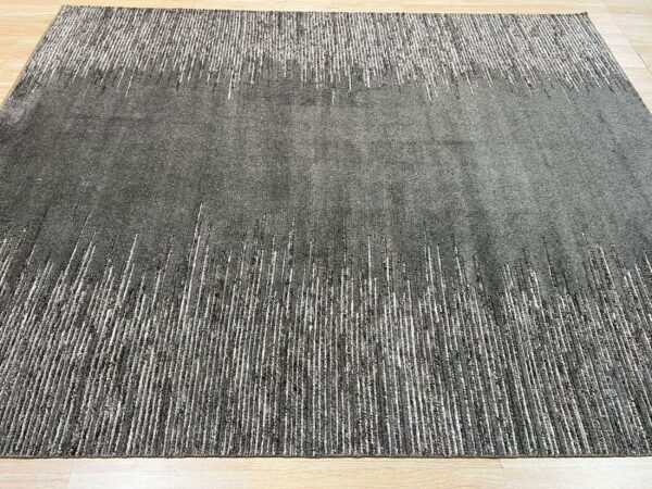 Charcoal gray textured rug featuring abstract vertical white dash patterns on a light wood floor.