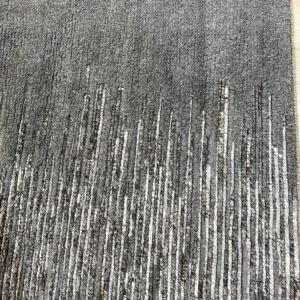 Textured dark gray rug featuring fading vertical white and black textured cords on wood flooring.