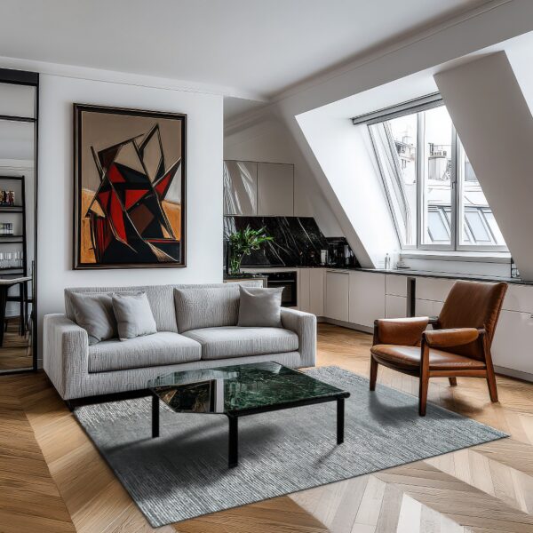 A slate gray striated rug anchors a modern living space with a gray sofa and a brown leather chair on parquet floors.