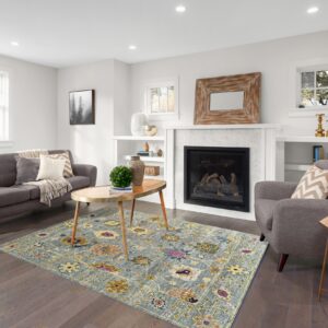 A distressed blue and gold floral rug defines a bright living room space with dark hardwood floors.