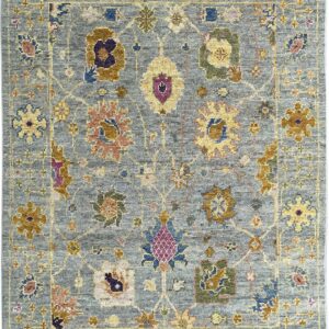 Textured blue-gray rug with a traditional pattern of multicolored floral and geometric medallions outlined in gold.