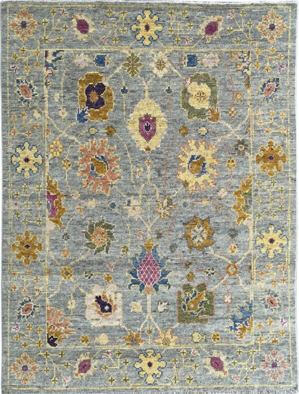 Textured blue-gray rug with a traditional pattern of multicolored floral and geometric medallions outlined in gold.