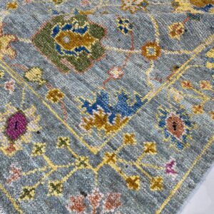 Close-up of a heathered blue-gray rug featuring traditional floral patterns in yellow, green, blue, and magenta.