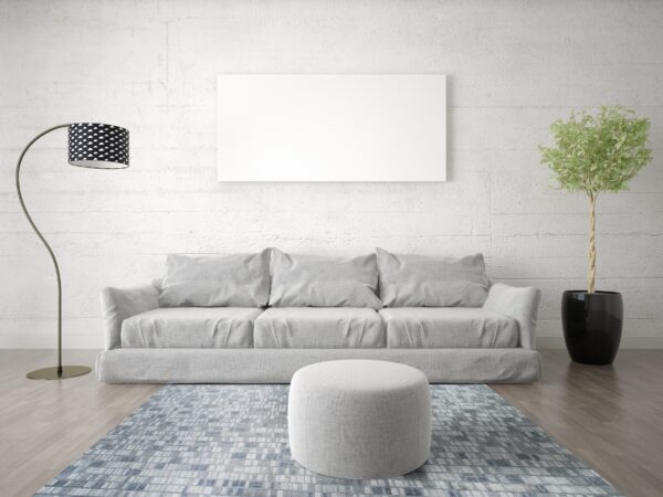 A blue and gray block patterned rug anchors a light grey sofa and ottoman on wood floors.