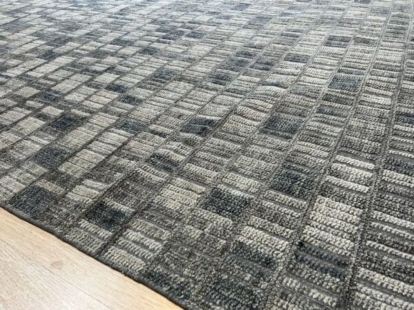 Textured gray rug featuring a mottled, alternating rectangular grid pattern on light wood floor.
