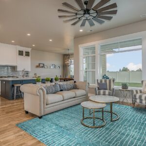 Teal and white striped rug lays on wood flooring beneath a light-colored sofa and marble nesting tables.