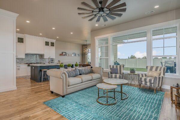 Teal and white striped rug lays on wood flooring beneath a light-colored sofa and marble nesting tables.