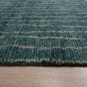 Close-up of a teal shaggy rug with irregular horizontal cream stripes resting on light wood flooring.