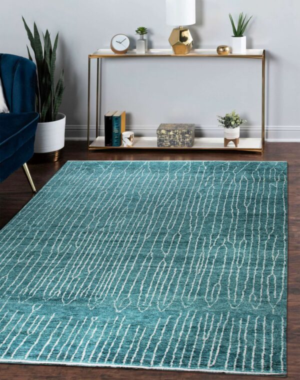 Teal rug featuring an abstract white linear pattern on dark wood floors with surrounding modern furniture.