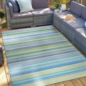 Multicolored striped outdoor rug anchors a gray woven sectional on a sunlit wooden deck.