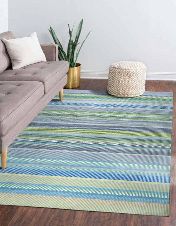 Multi-colored striped rug featuring blue, green, and gray sits on wood floor next to a gray sofa.