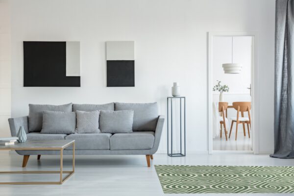 Low pile green and cream geometric rug brightens a modern living room with a gray couch.