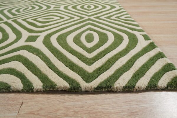 A green and cream sculpted high-pile rug with a bold geometric diamond pattern on wood flooring.