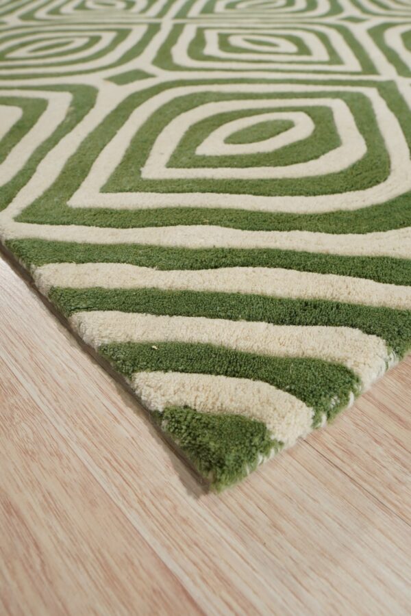 Close-up of a shaggy green and cream geometric rug resting on light blonde plank flooring.