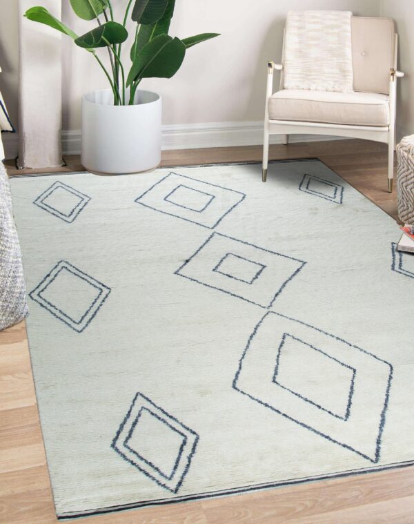 Light cream rug featuring large dark blue diamond outlines placed beneath a chair and plant.