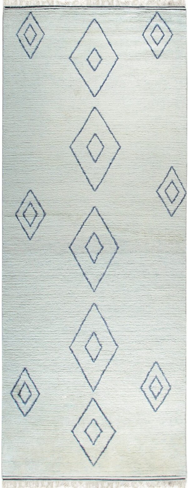 Lightly textured off-white rug featuring dark blue geometric diamond shapes and fringe ends.