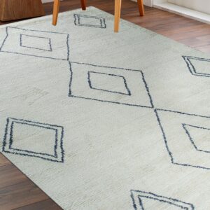 Cream textured rug with dark blue geometric diamond patterns on a dark wood floor.