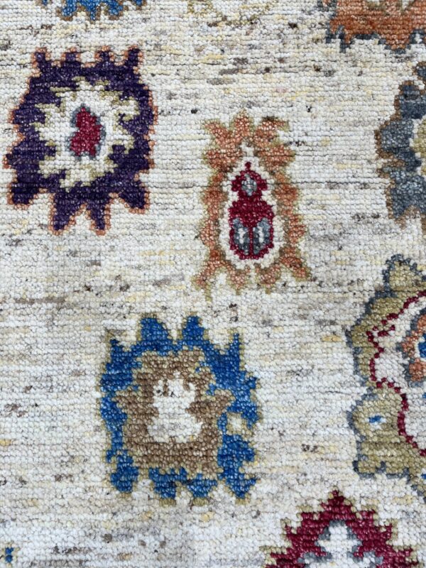 Textured cream rug with traditional multicolored medallions in purple, blue, red, and orange tones.