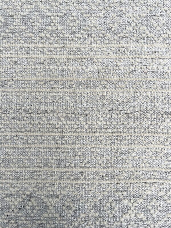 Gray and cream textured rug showing raised horizontal bands and bouclé-like spotted details.