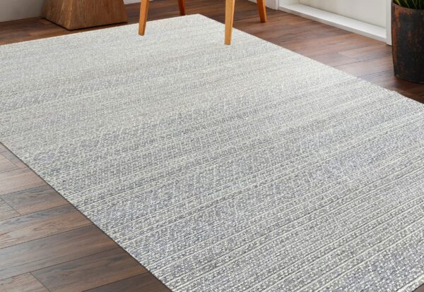Heathered gray and white low-pile rug with prominent linear stripes anchors dark hardwood flooring.