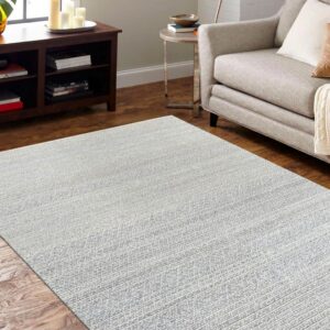 Textured gray and white rug anchors a living space with hardwood floors and a beige sofa.