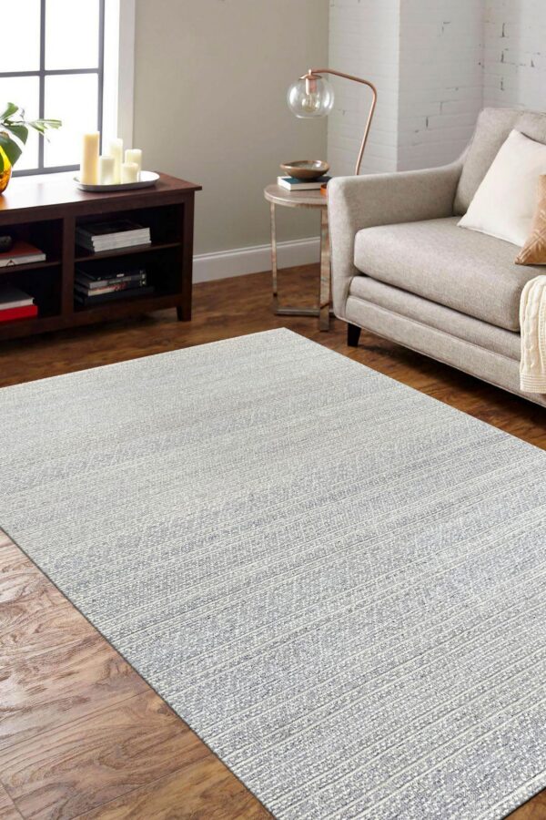 Textured gray and white rug anchors a living space with hardwood floors and a beige sofa.