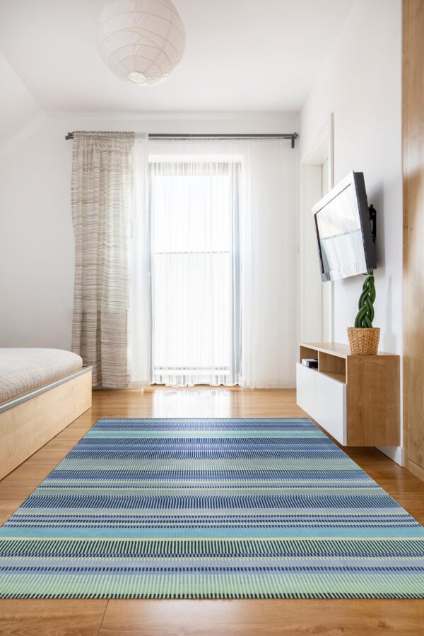 A blue, teal, and lime striped rug covers a wood floor in a brightly lit, modern room.